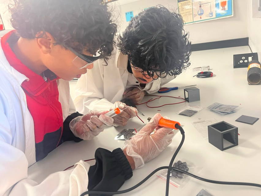 Two engineers soldering payload electronics on the bench